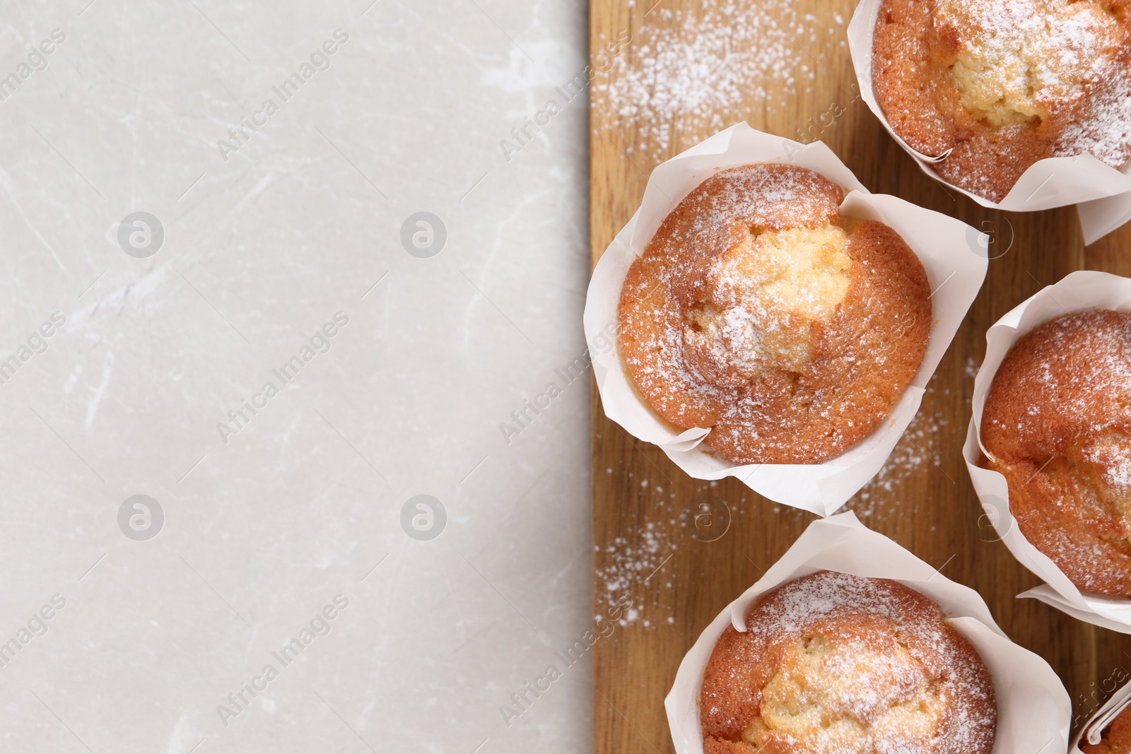 Photo of Delicious muffins on light table, top view. Space for text