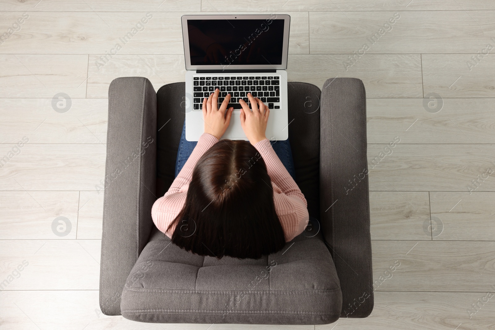 Photo of Woman working with laptop in armchair, top view