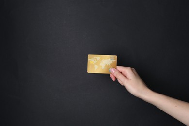 Photo of Woman holding credit card on black background, closeup