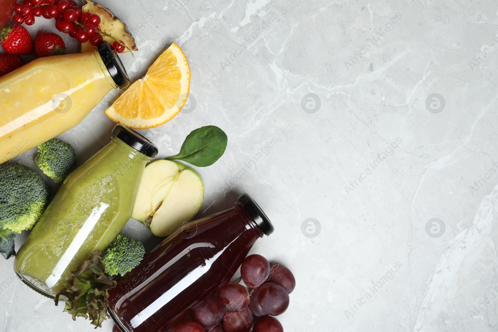 Photo of Bottles of delicious juices and fresh fruits on marble table, flat lay. Space for text