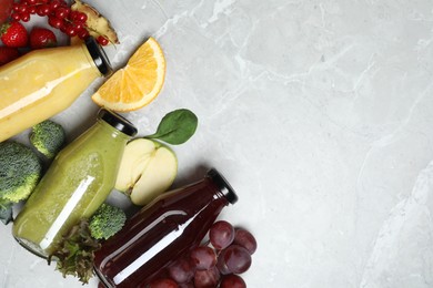 Bottles of delicious juices and fresh fruits on marble table, flat lay. Space for text