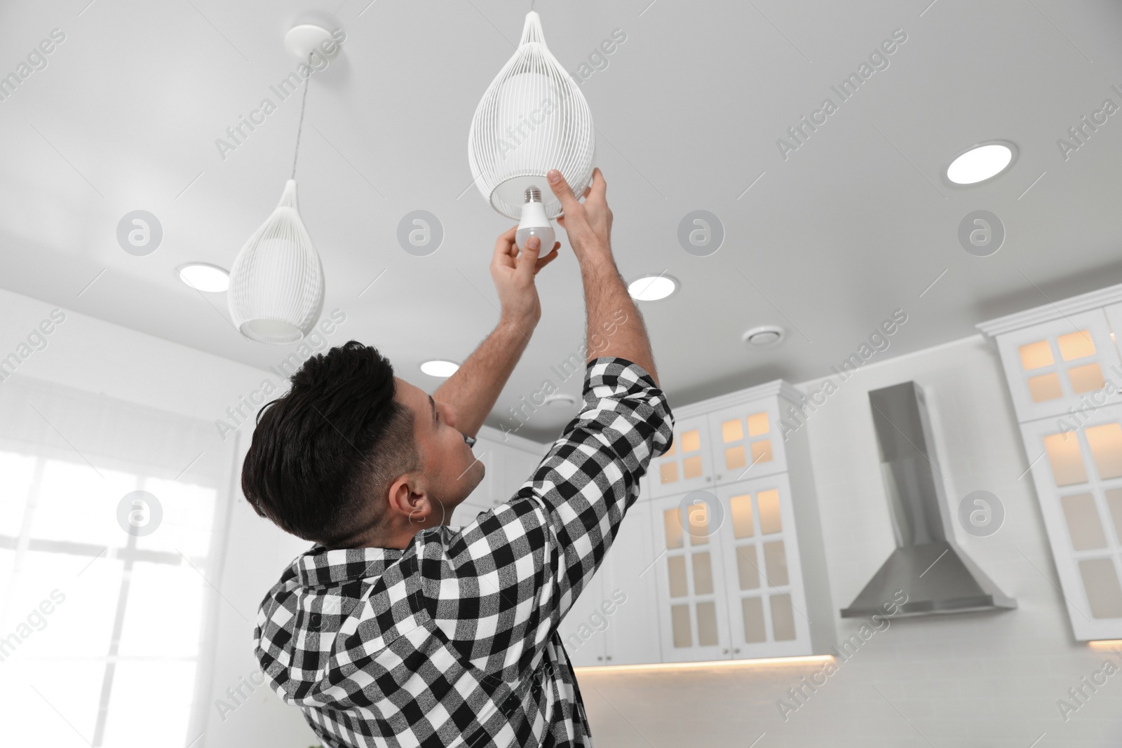 Photo of Man changing light bulb in lamp at home