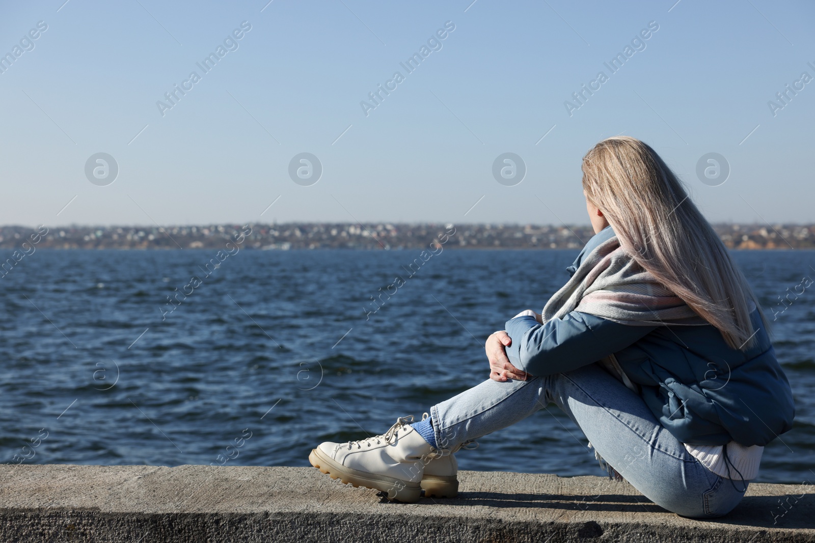 Photo of Lonely woman sitting near river on sunny day