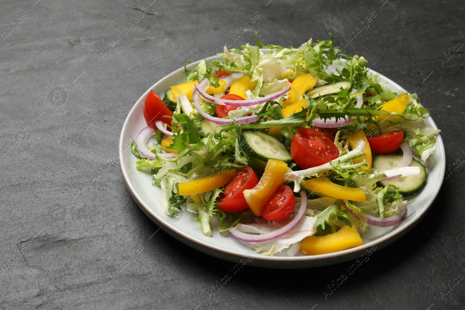 Photo of Tasty fresh vegetarian salad on black table, space for text