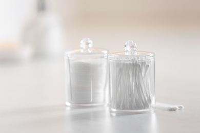 Photo of Cotton buds and pads in transparent holders on table indoors, space for text