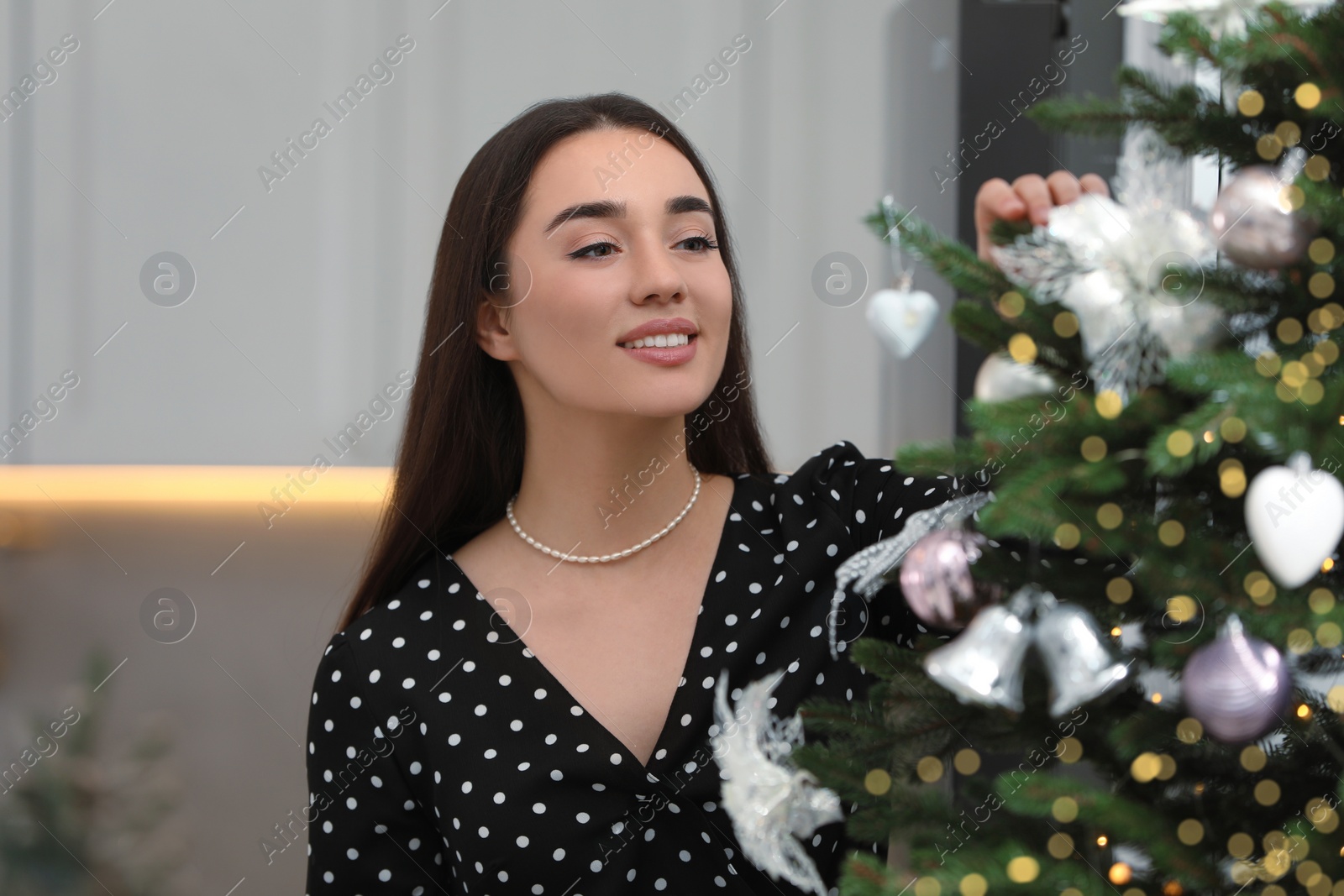 Photo of Smiling woman decorating Christmas tree in room