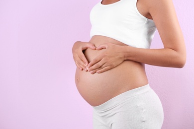 Photo of Pregnant woman posing on color background, closeup. Space for text