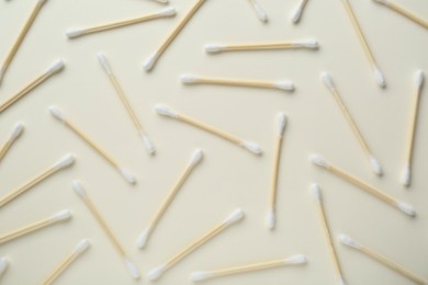 Many wooden cotton buds on beige background, flat lay