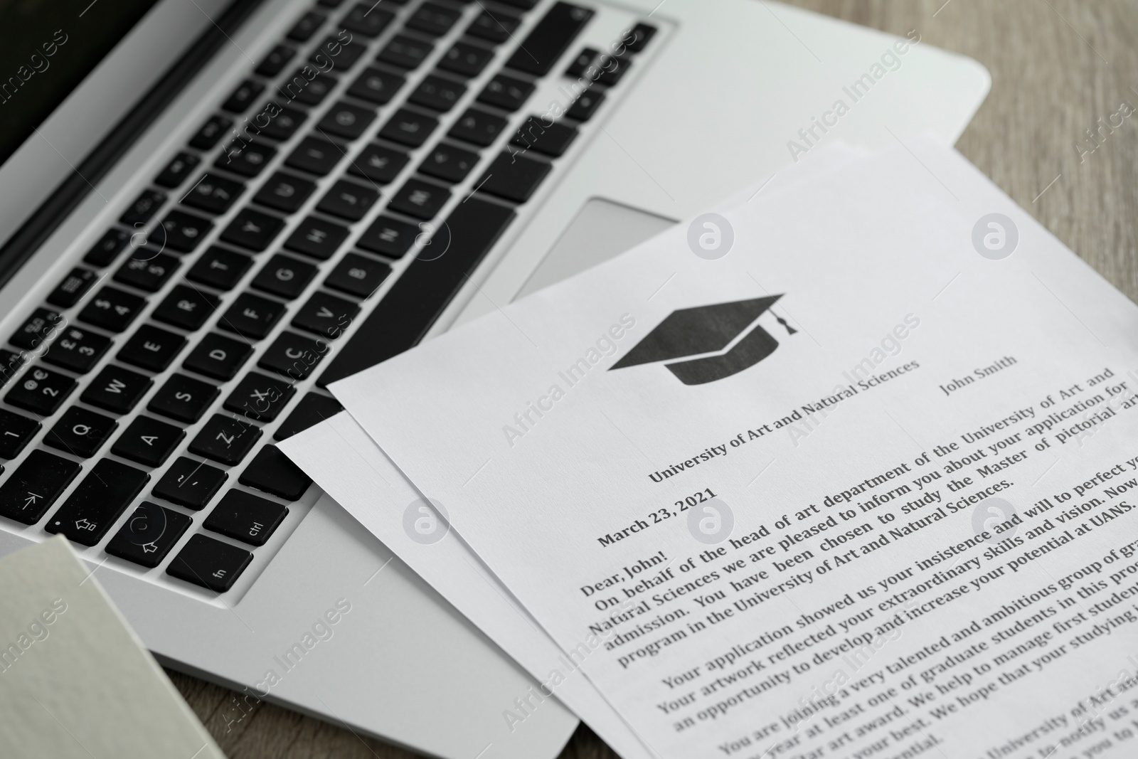 Photo of Acceptance letters from universities and laptop on wooden table indoors, closeup