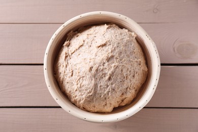 Fresh sourdough in proofing basket on wooden table, top view