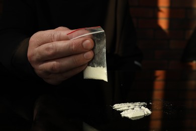 Drug addiction. Man with cocaine at black table, closeup