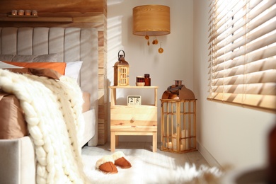 Photo of Cozy bedroom interior with vintage lanterns and knitted blanket