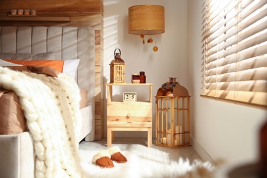 Cozy bedroom interior with vintage lanterns and knitted blanket