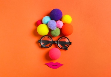 Photo of Funny face made with clown's accessories on red background, flat lay