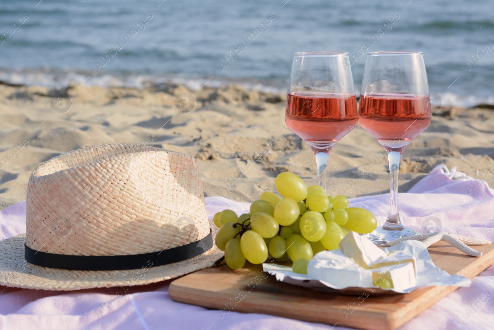 Photo of Glasses with rose wine and snacks for beach picnic on sandy seashore