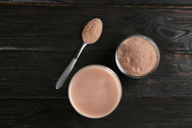 Photo of Protein shake and powder on black wooden table, flat lay