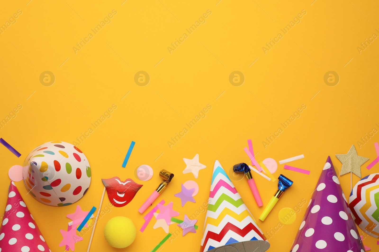 Photo of Flat lay composition with party hats and other festive items on orange background. Space for text