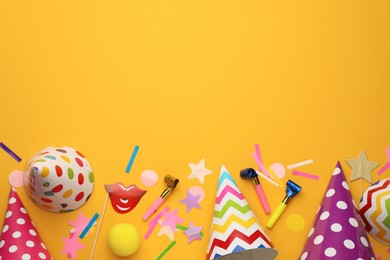 Photo of Flat lay composition with party hats and other festive items on orange background. Space for text