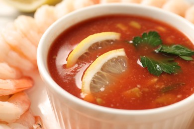 Photo of Tasty boiled shrimps with cocktail sauce and lemon on plate, closeup