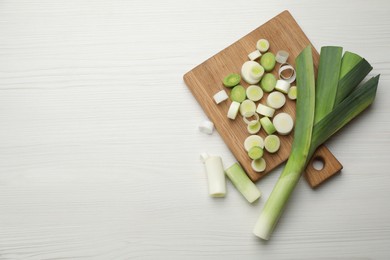 Photo of Fresh raw leeks on white wooden table, flat lay. Space for text