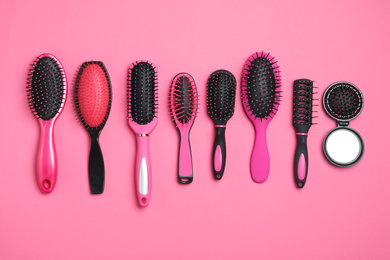 Photo of Flat lay composition with modern hair brushes on pink background