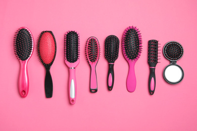 Flat lay composition with modern hair brushes on pink background