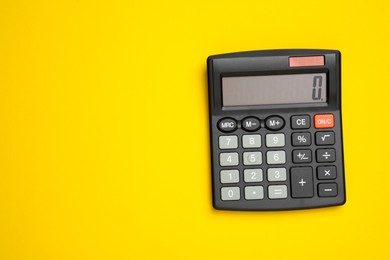 Photo of Black calculator on yellow background, top view. Space for text