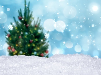 Image of Snow and blurred view of beautiful decorated Christmas tree. Bokeh effect