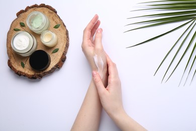 Woman applying hand cream on white background, top view