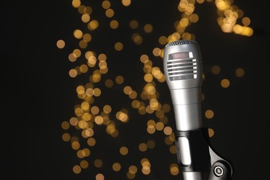 Photo of Sound recording and reinforcement. Microphone against black background with blurred lights, closeup. Space for text.
