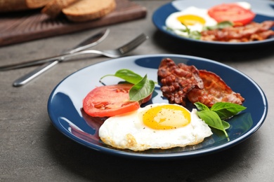 Photo of Fried sunny side up egg with tomato and bacon served on table