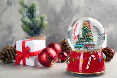 Photo of Beautiful Christmas snow globe and festive decor on light table