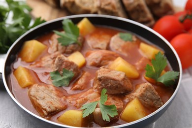Photo of Delicious goulash in saucepan on table, closeup