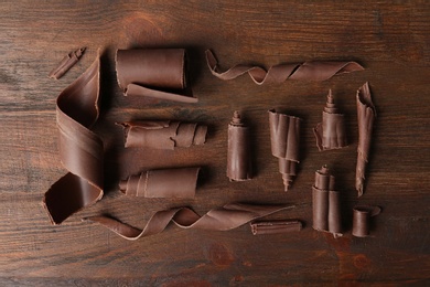 Chocolate curls on wooden background, flat lay