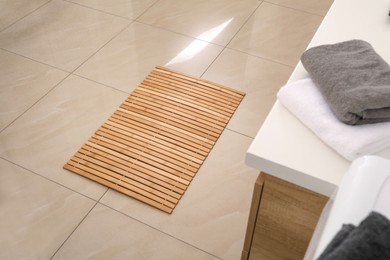 Photo of Wooden mat on floor in bathroom. Interior design
