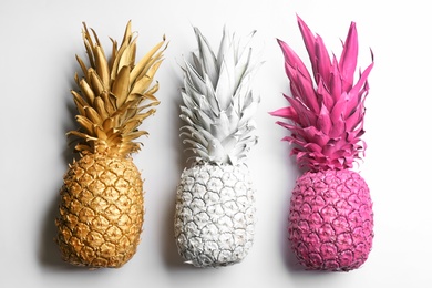 Photo of Painted pineapples on white background, top view. Creative concept
