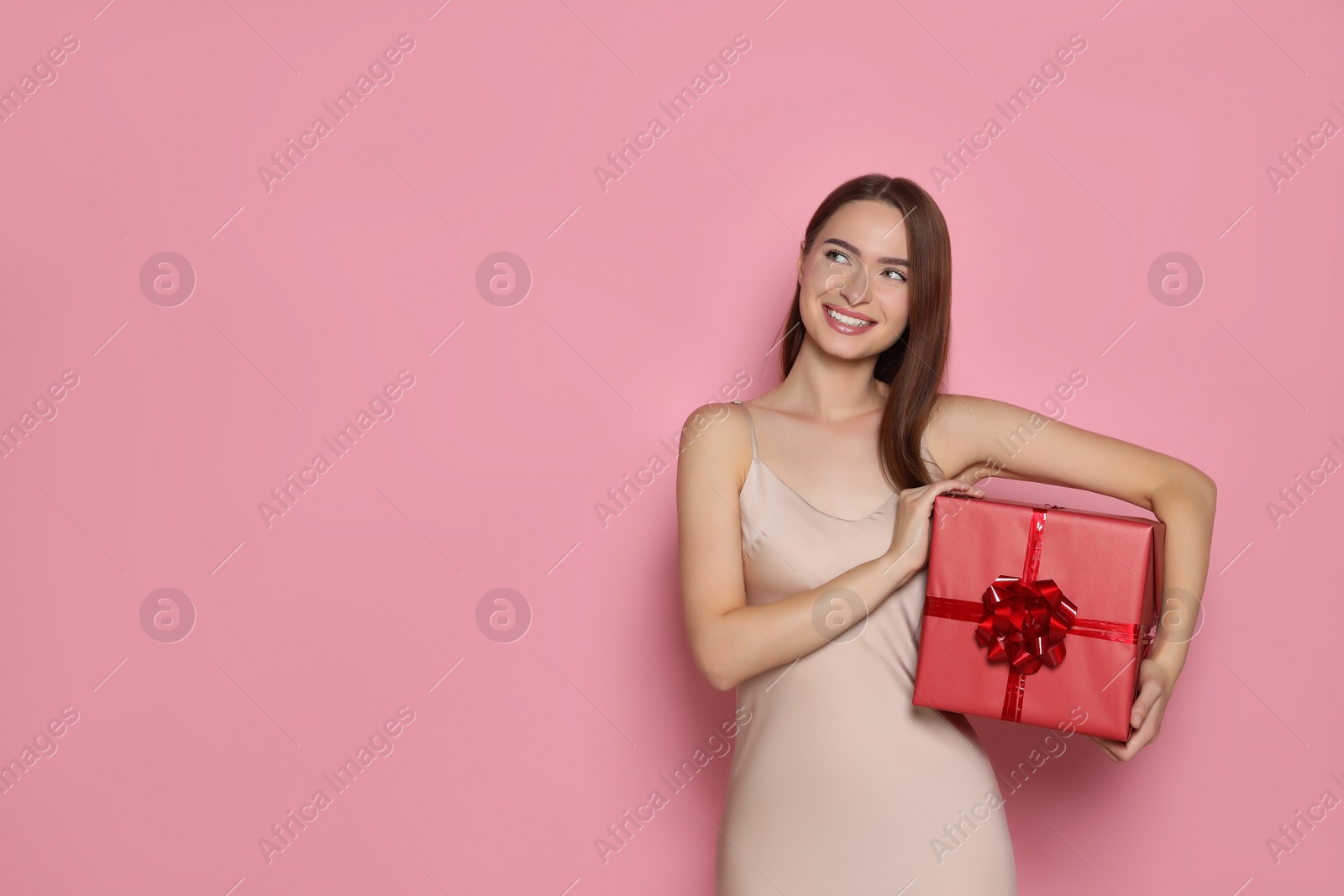 Photo of Portrait of happy young woman with gift box on pink background. Space for text