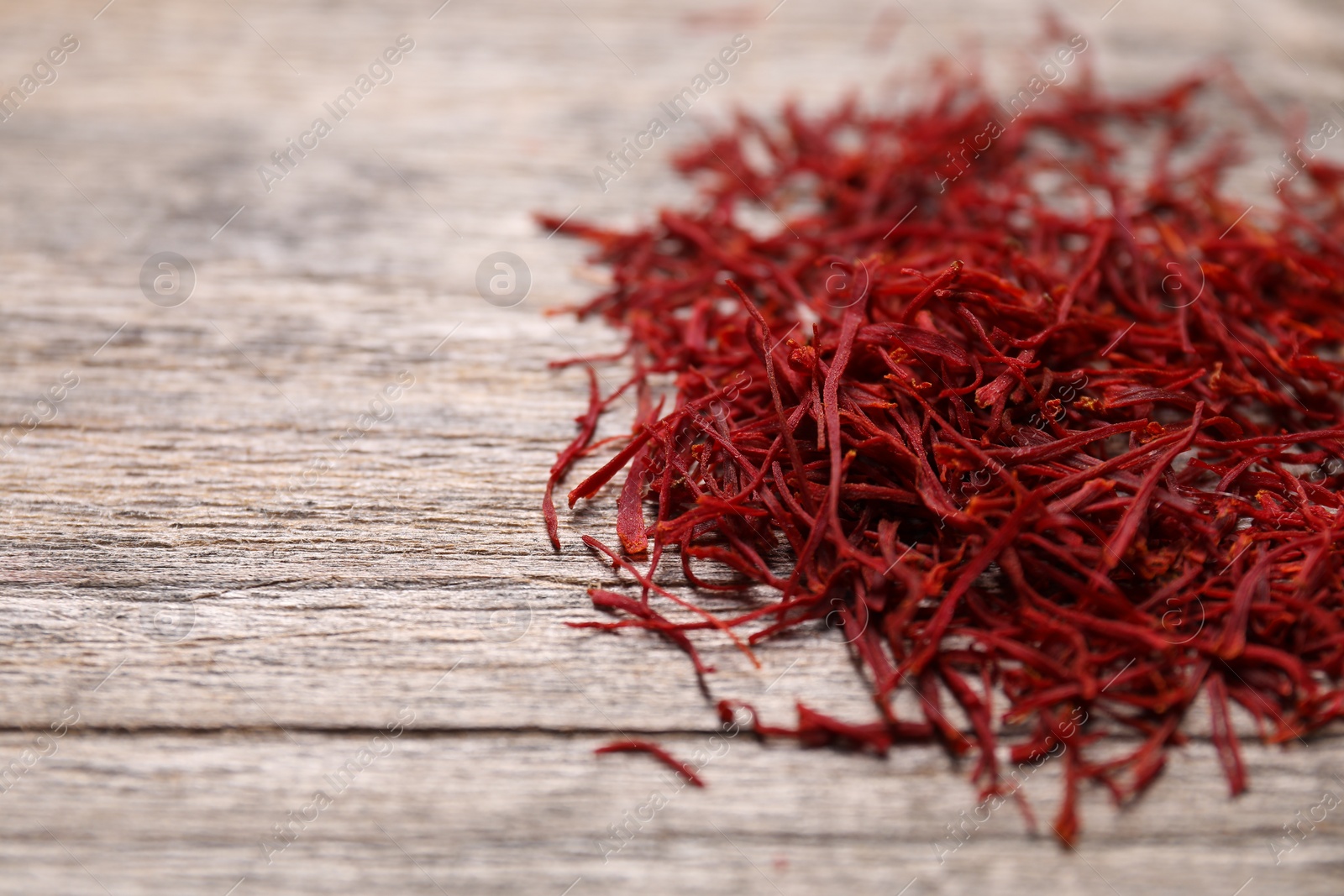 Photo of Aromatic saffron on wooden table, closeup. Space for text