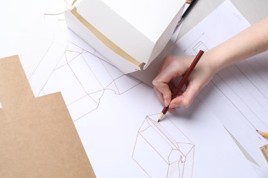 Woman creating packaging design at table, top view