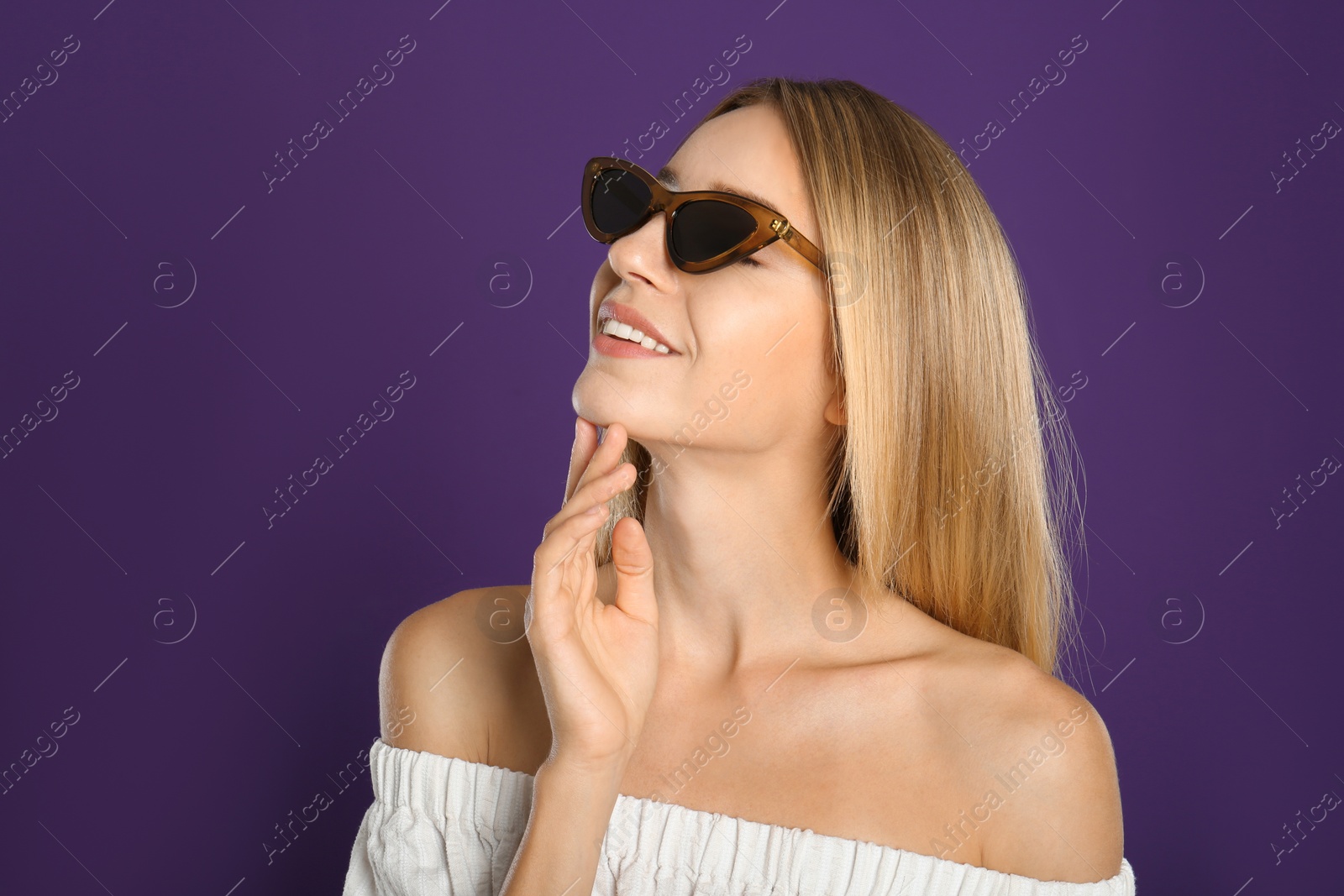 Photo of Beautiful woman in stylish sunglasses on purple background