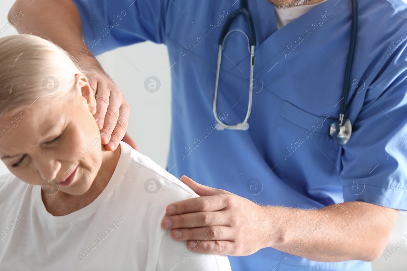 Photo of Male orthopedist examining patient with injured neck, closeup