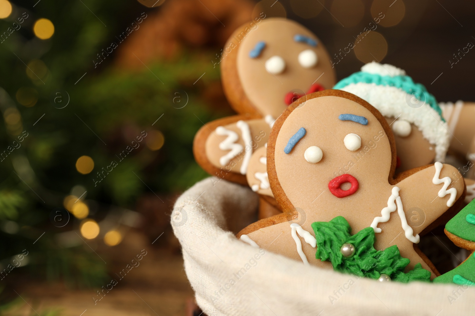 Photo of Delicious homemade Christmas cookies in bowl against blurred festive lights, closeup. Space for text
