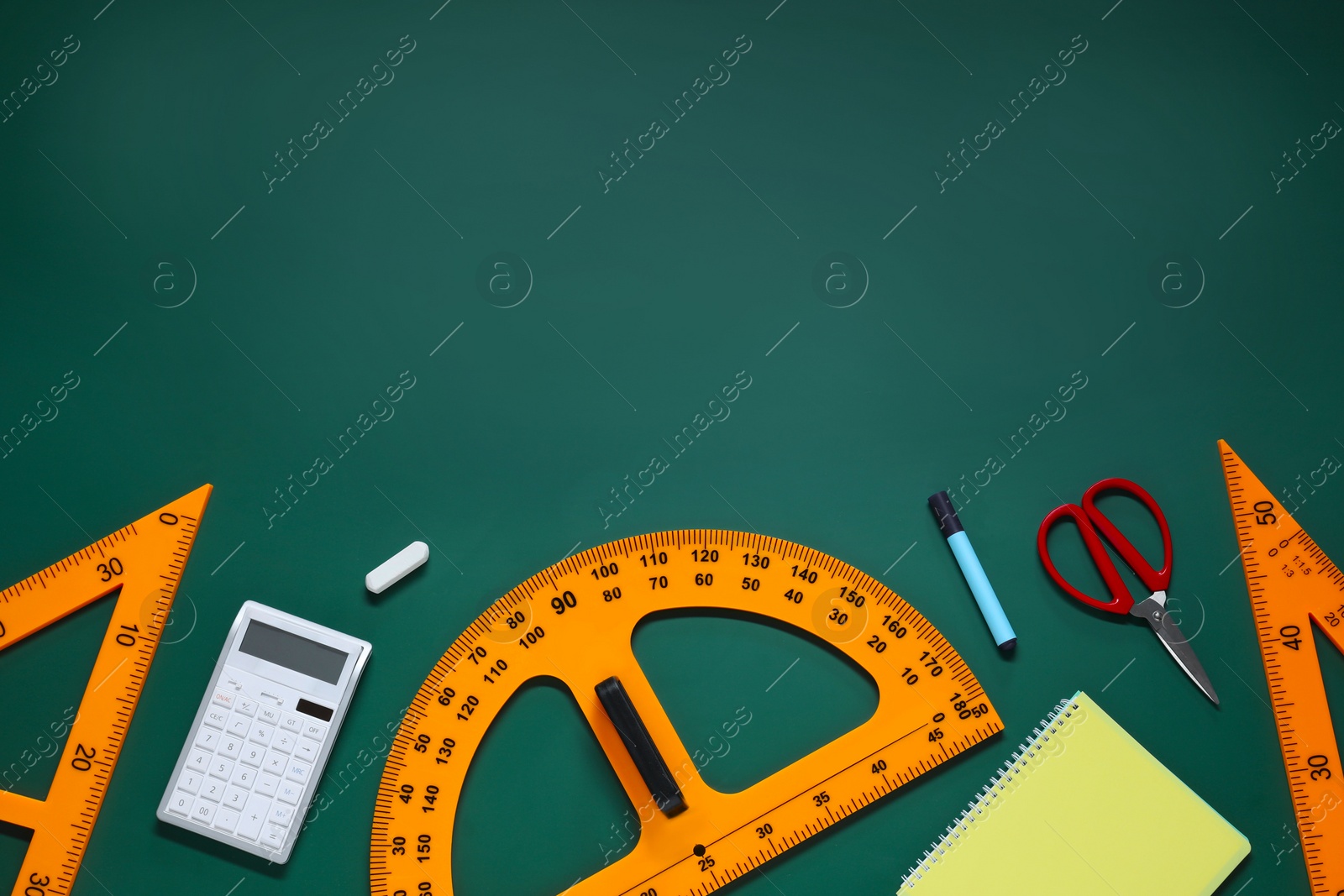 Photo of Flat lay composition with protractor, triangle and stationery on green chalkboard. Space for text