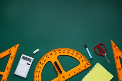 Photo of Flat lay composition with protractor, triangle and stationery on green chalkboard. Space for text
