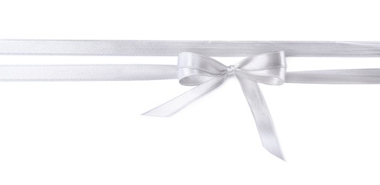 Silver satin ribbons with bow on white background, top view