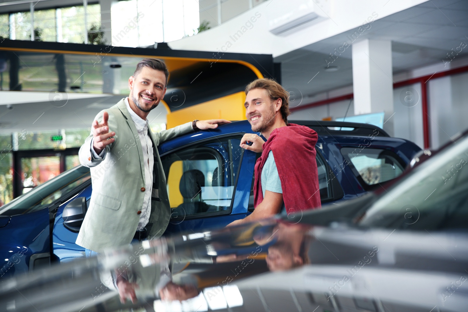 Photo of Salesman with customer in modern car dealership