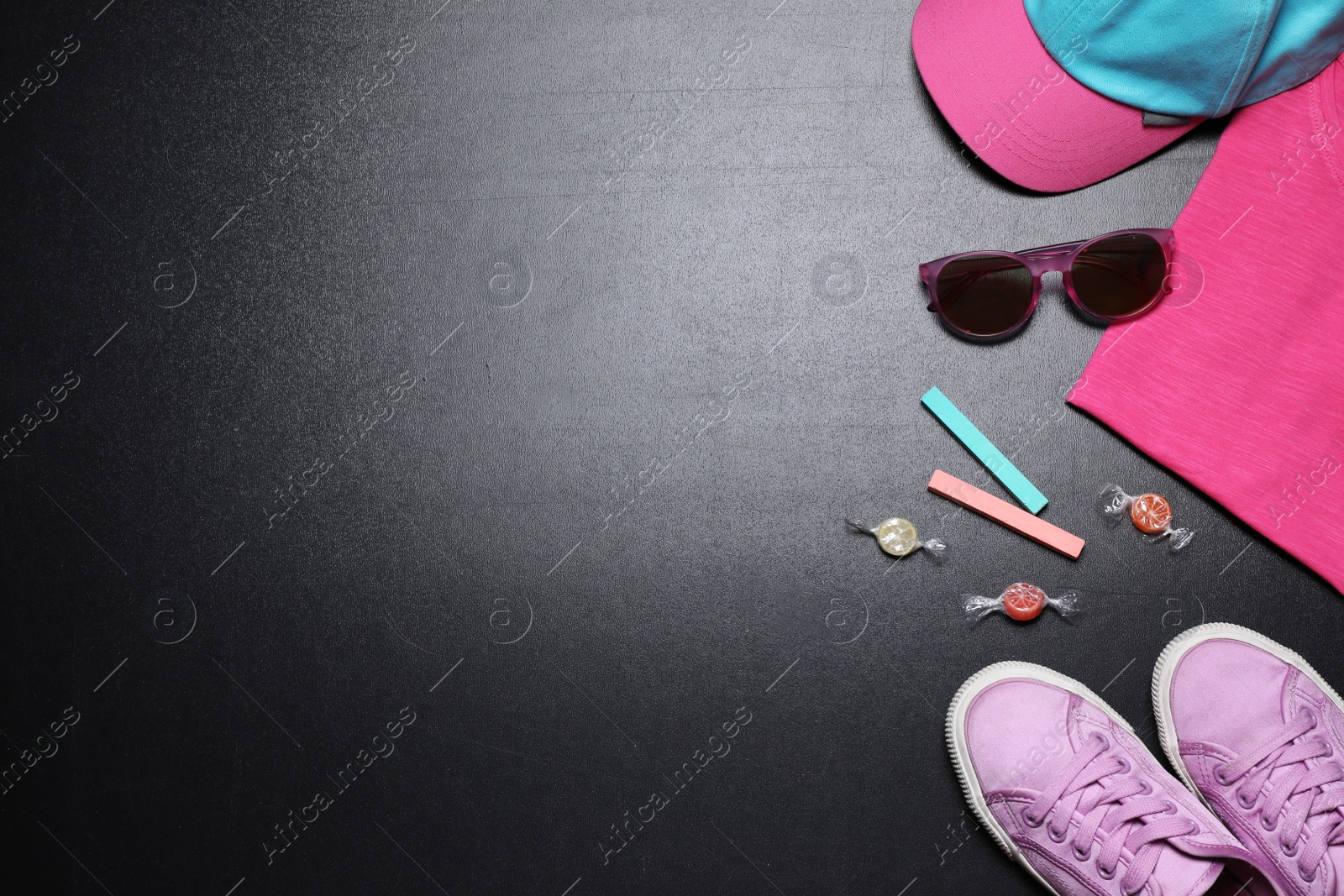 Photo of Flat lay composition with child's shoes on blackboard, space for text. School holidays