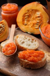 Photo of Slices of bread with delicious pumpkin jam and fresh pumpkin on wooden table, closeup