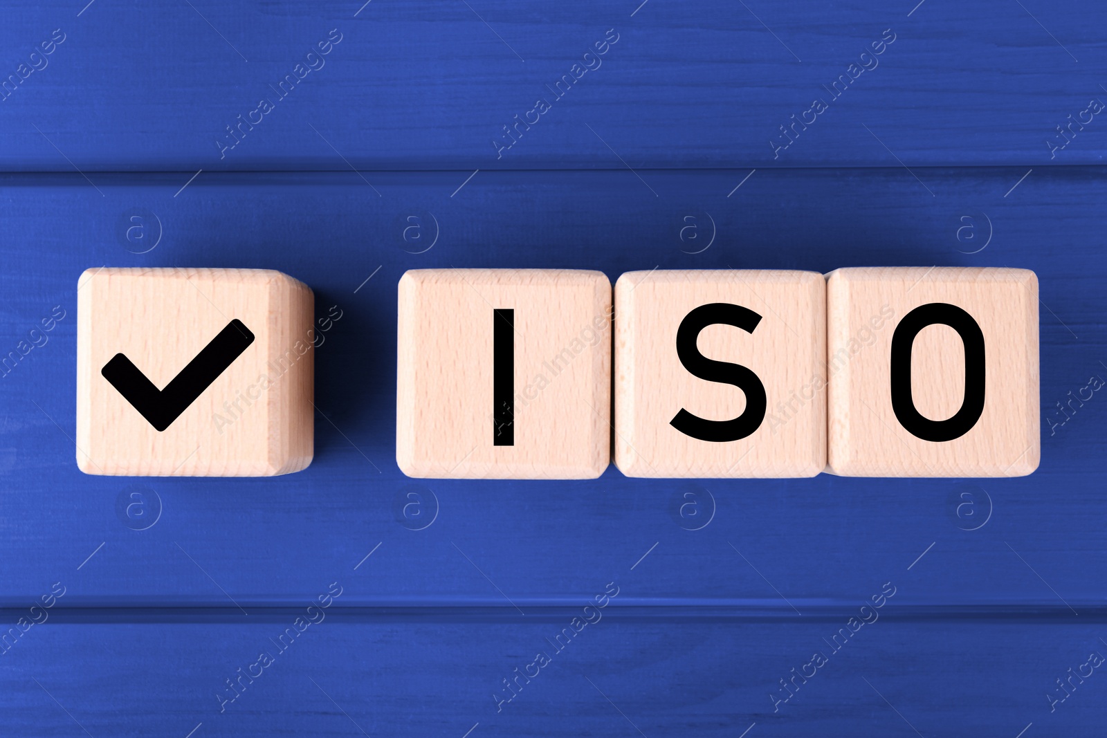 Photo of International Organization for Standardization. Cubes with check mark and abbreviation ISO on blue wooden table, flat lay