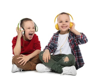 Photo of Portrait of cute twin brothers with headphones sitting on white background